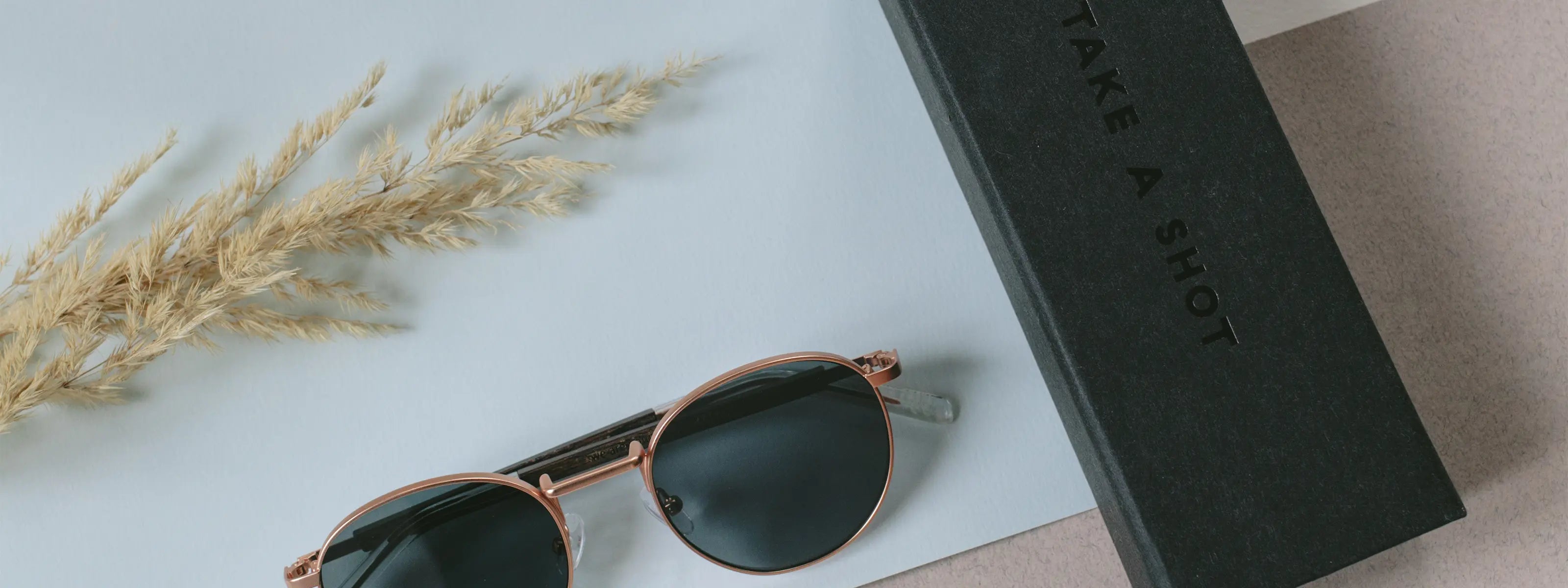 Eine nachhaltige Sonnenbrille und ein Etui aus Zellstoff liegen auf hellem Schreibtisch