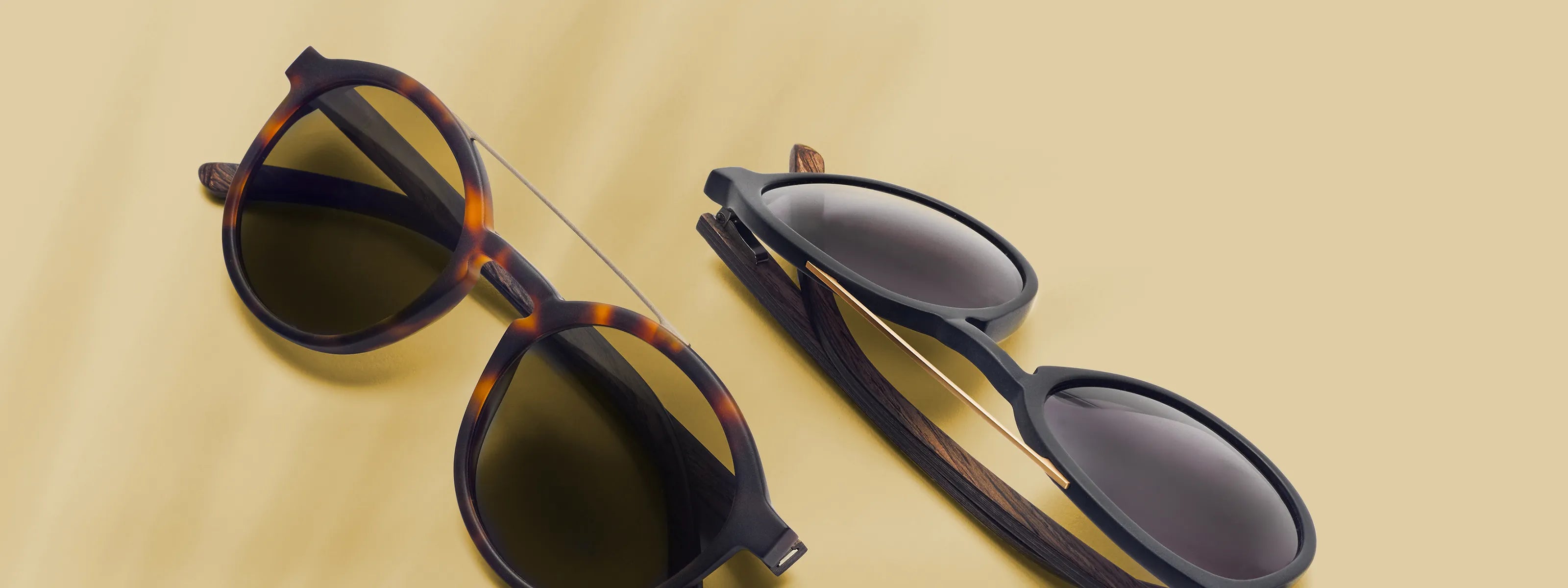 Zwei nachhaltige Take A Shot Sonnenbrillen auf hellem Hintergrund