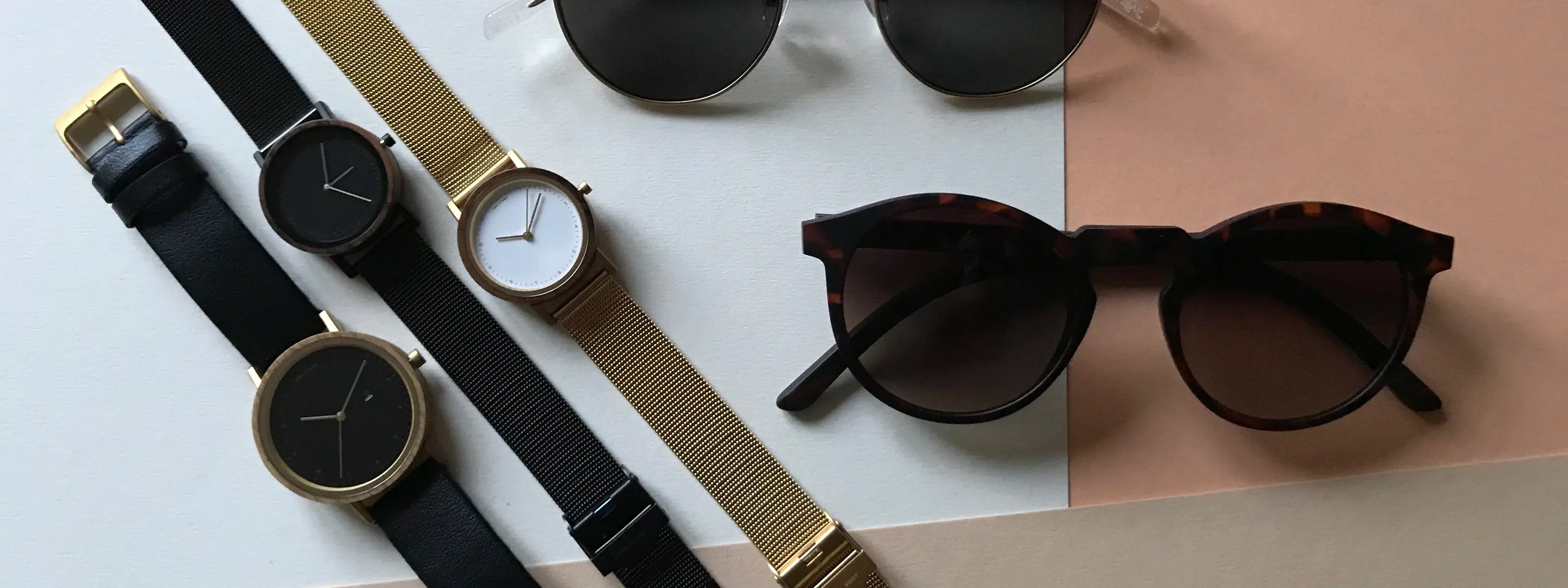 Nachhaltige Sonnenbrillen und Uhren von Take A Shot liegen auf einem hellen Schreibtisch