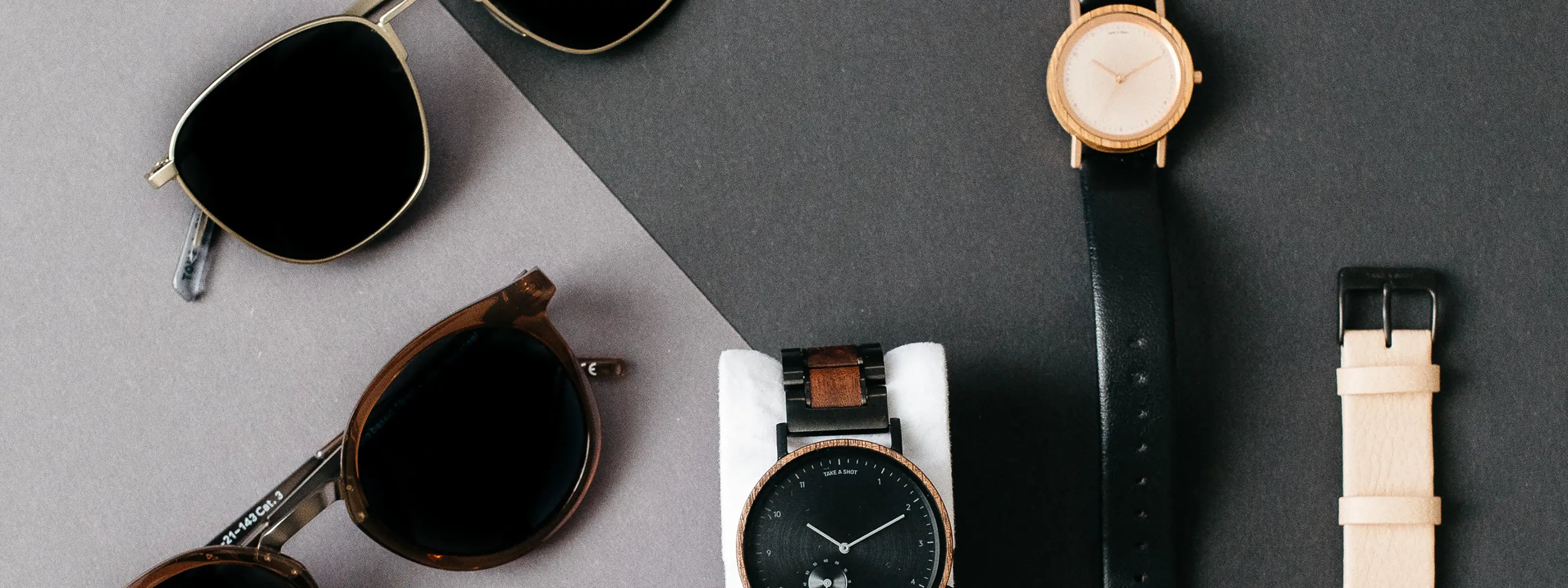 Nachhaltige Sonnenbrillen und Armbanduhren von Take A Shot liegen auf dunklem Hintergrund