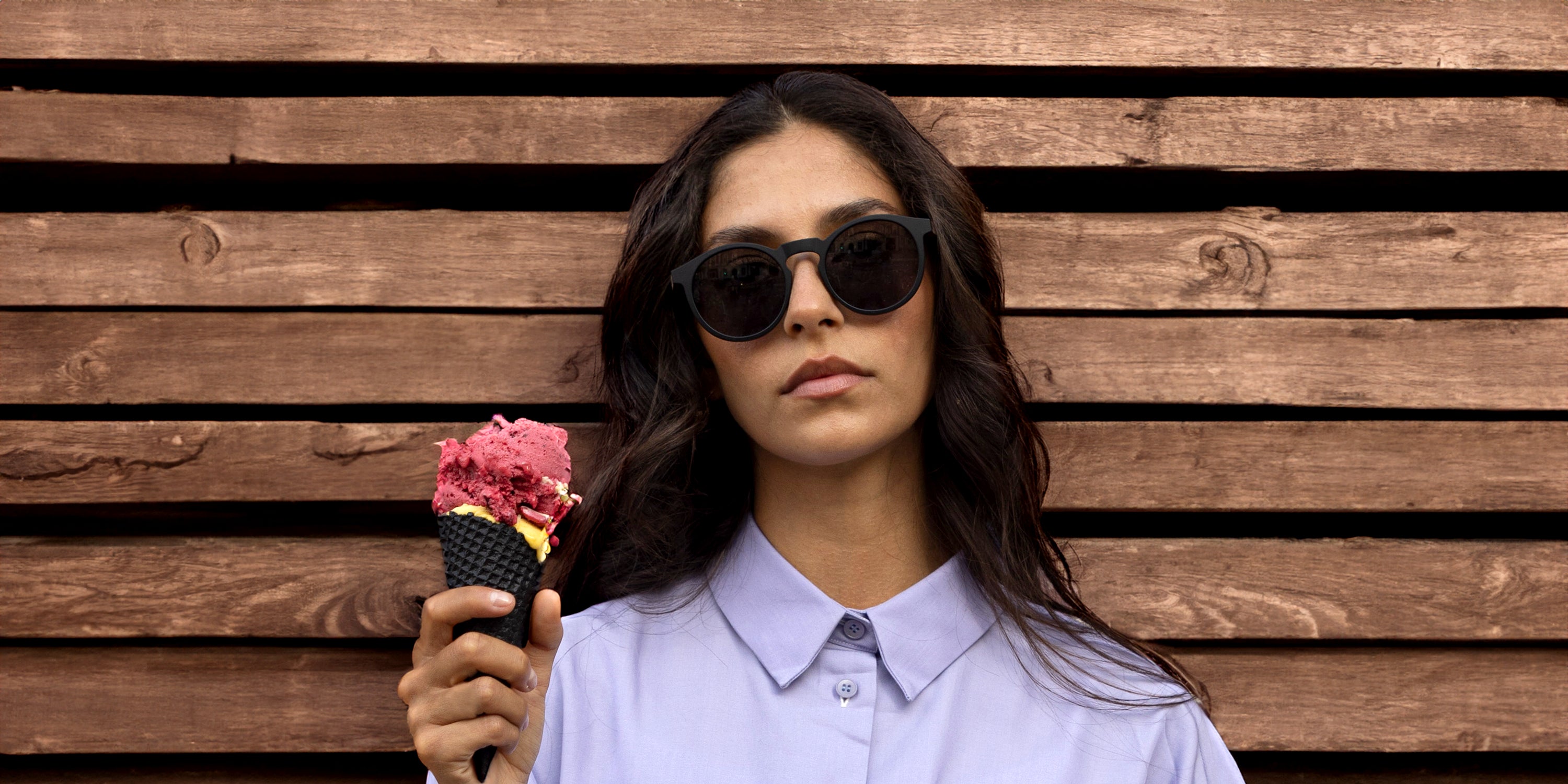 Frau trägt Take A Shot Sonnenbrille und isst Eis.webp